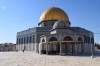 The Dome of the Rock in full view against a clear, blue sky. The richly coloured tiles and golden dome shine brightly in the sun while people gather outside.  thumbnail